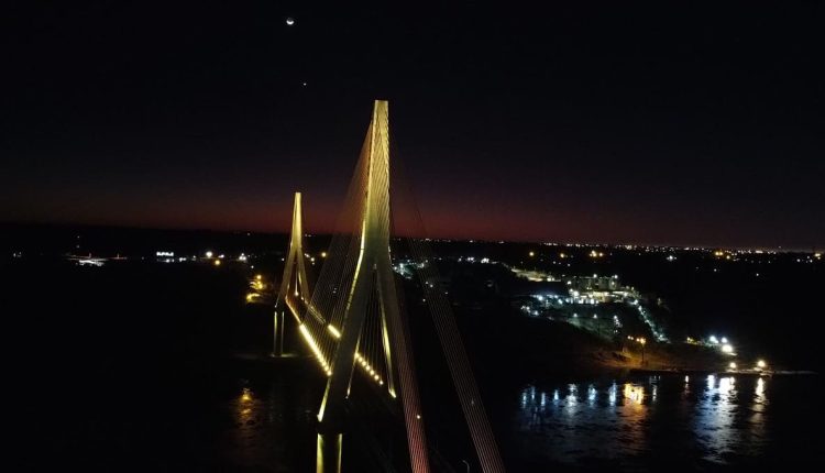 Panorama da iluminação temática da ponte, com a margem paraguaia ao fundo. Imagem: Gentileza/DER-PR