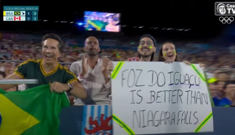 Cartaz apareceu na transmissão da final feminina do vôlei de praia, vencida pela dupla brasileira Ana Patricia e Duda. Imagem: Reprodução/Cazé TV/Paris 2024